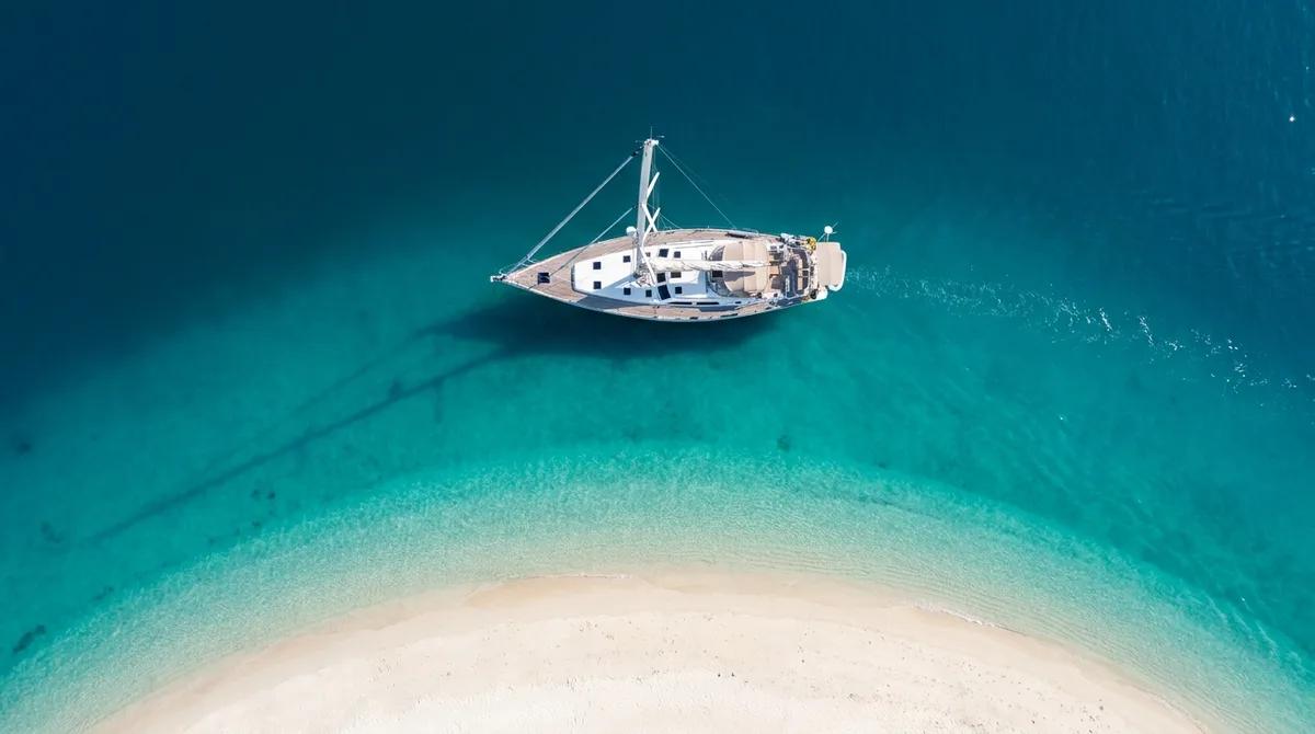 Illustrative yacht at anchor in turquoise water